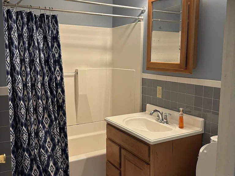 Tiled bathroom with tub/shower combination.