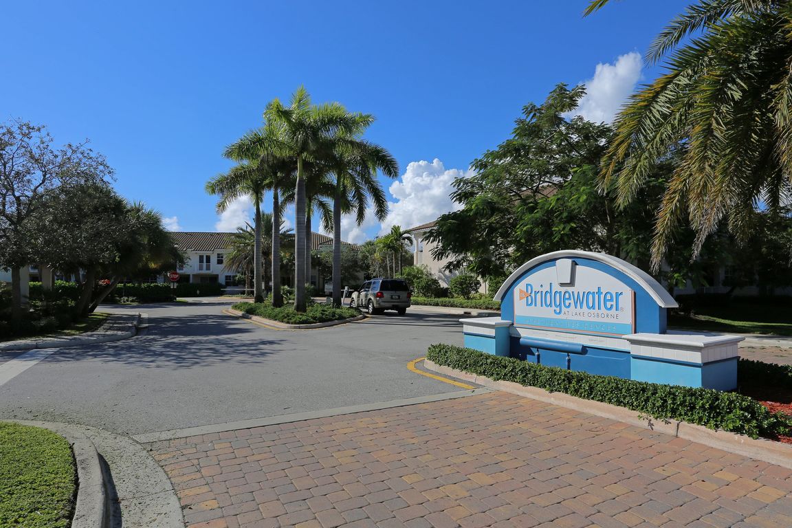 Inviting entrance to Bridgewater at Lake Osborne with palm trees and a sunny, welcoming atmosphere.