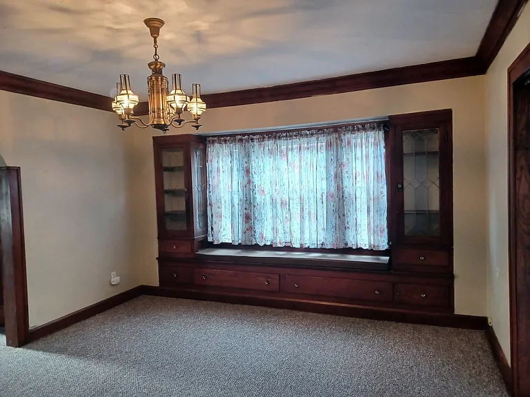 Dining room built in lead-glass cabinets, storage drawers, and window seat with cushion and window treatments.