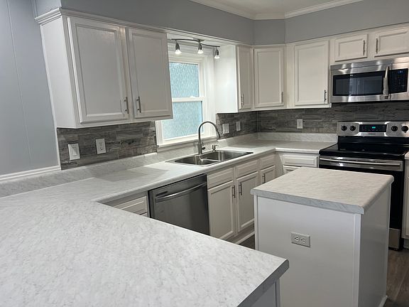 All new kitchen with lots of cabinets, new stainless appliances, tile back splash, marble look counter tops and counter bar.