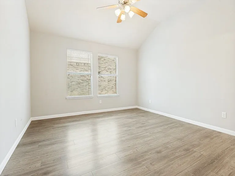 Large windows with blinds in primary bedroom.
