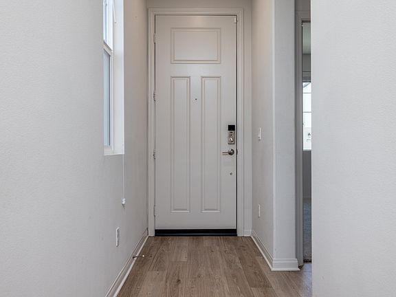 Bright and welcoming entryway with laminate flooring and modern white door, creating a clean and inviting first impression that leads seamlessly into the home's open layout.
