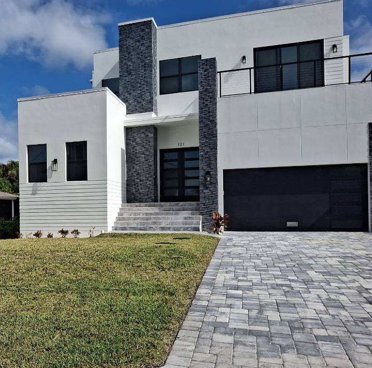121 West Hilo front view. It includes a two-car garage with driveway parking and an outdoor wrap-around deck on the second floor.