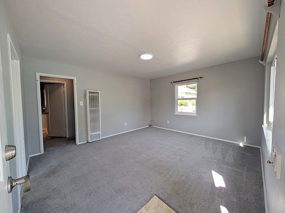 POV from front door looking at living room. Kitchen on left, straight through threshold of door is the bathroom. To the right of the bathroom is the first bedroom. On the left of the bathroom is the stairs up to the second bedroom and large walk-in closet