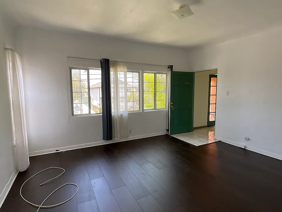 Entrance into the unit is a large living room with wood flooring and blinds