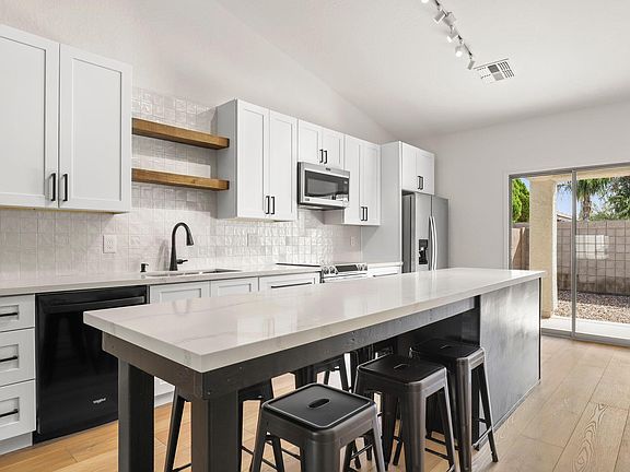 Brand-new kitchen with 10' Island with Seating for up to 7, Stunning Zellinge Tile Backsplash, Floating Wood Shelves above XL Sink, Designer 42" Cabinets, Professional Series Stainless Steel Slide-In Range, and Trendy Matte Black Hardware.