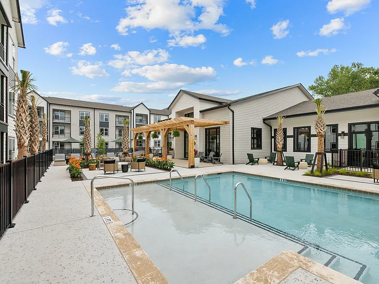 Modern apartment community pool with tanning ledge, outdoor seating, and resort-style amenities for relaxation and entertaining.