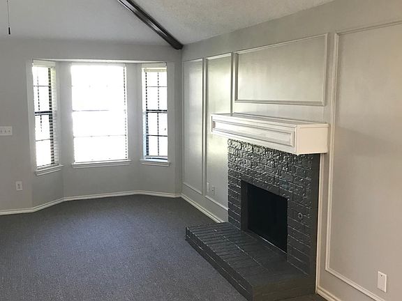 Living area has new paint and new carpet with bay windows at the front of the house to let in plenty of sunlight. A sliding door to the side patio is to the right of the fireplace area (not seen in picture).