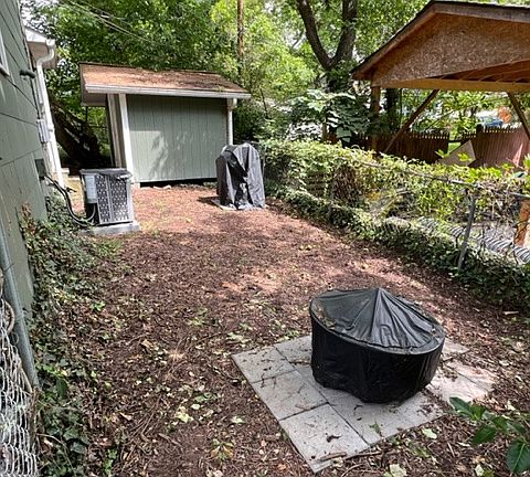 fenced backyard area with fire pit, wood/smoker grill provided by landlord