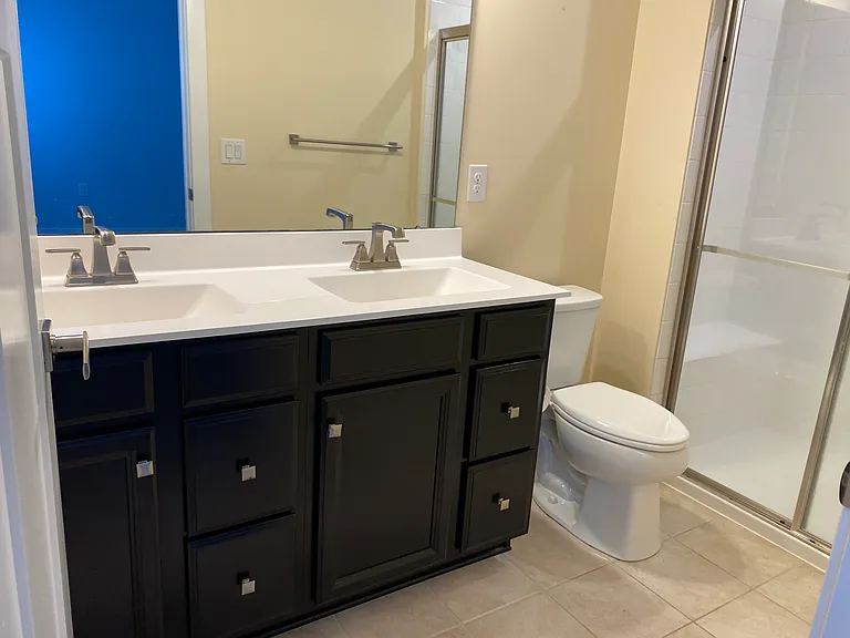 Master's bedroom ensuite bathroom with double sinks and shower. Tiled floor.