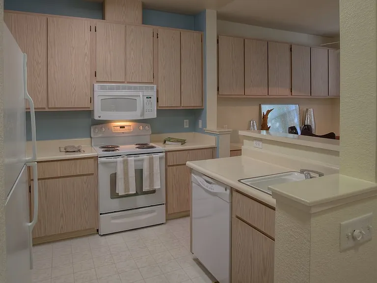 Classic Package I kitchen with light oak cabinetry, white laminate countertops, white appliances, and hard surface flooring