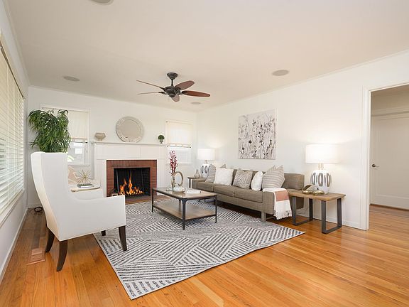 Light-filled and inviting, the living room displays a handsome fireplace and is fitted for surround sound and equipped with a ceiling fan.