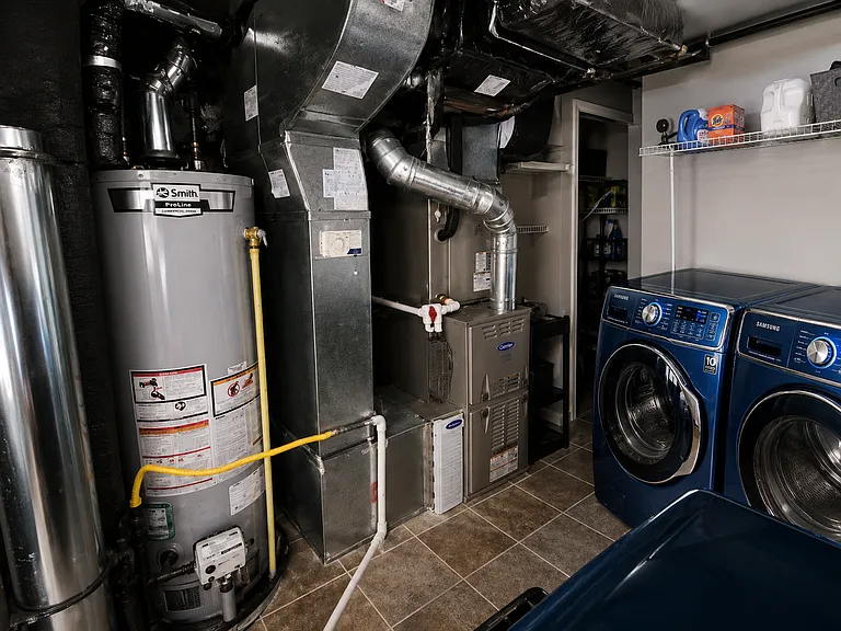 A spacious laundry and utility room features premium Samsung front-load washer and dryer units with oversized capacity, making laundry day effortless for busy households.