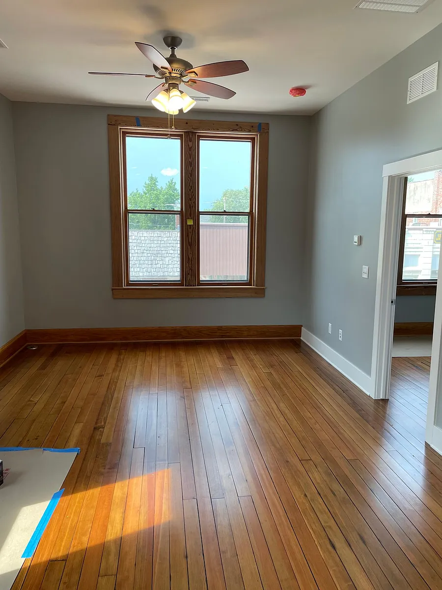 Same room looking north into living space. Restored original front window overlooking city street. Refinished hardwood floors throughout. - 204 E Broadway Ave #A