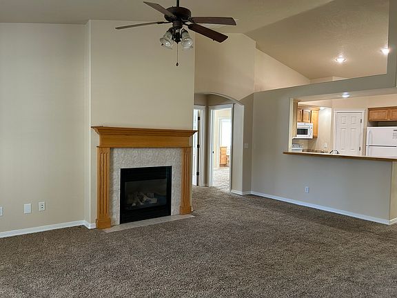 Living room from the kitchen side of the room. Lights and fan in the center of the room hang from the vaulted ceiling.