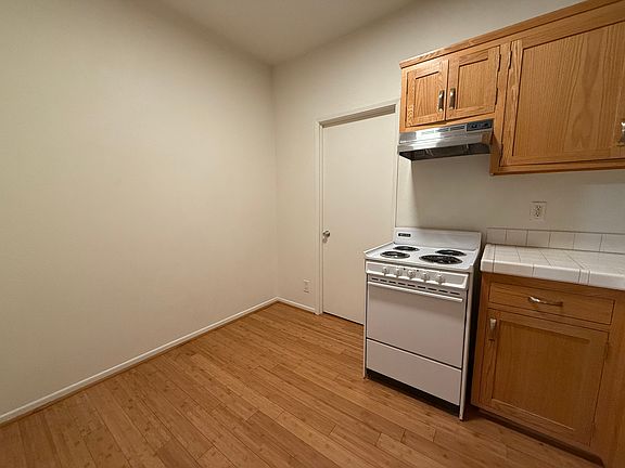 Kitchen with useable space to the left of the oven and cabinets for storage, small table, or bar stool seating.