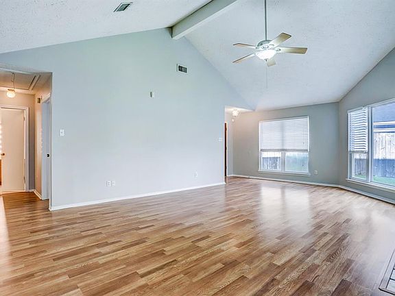 Spacious living room features high ceilings with cooling ceiling fan. Picture window offers views to well sized yard.
