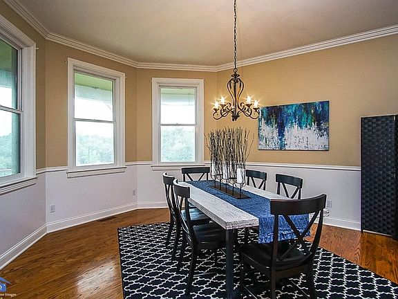 Formal dining room with hardwood floors and crown molding has bay window that overlooks the front lawn.
