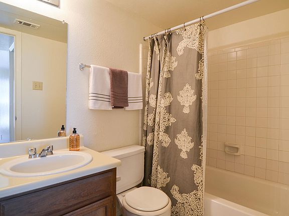 A bathroom with a tub, cabinet storage, and a wide mirror over the sink