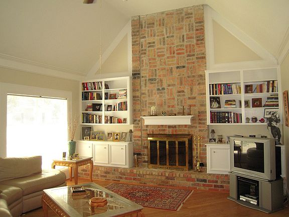 Living area with tall ceilings, wood floors and a wood burning fireplace.