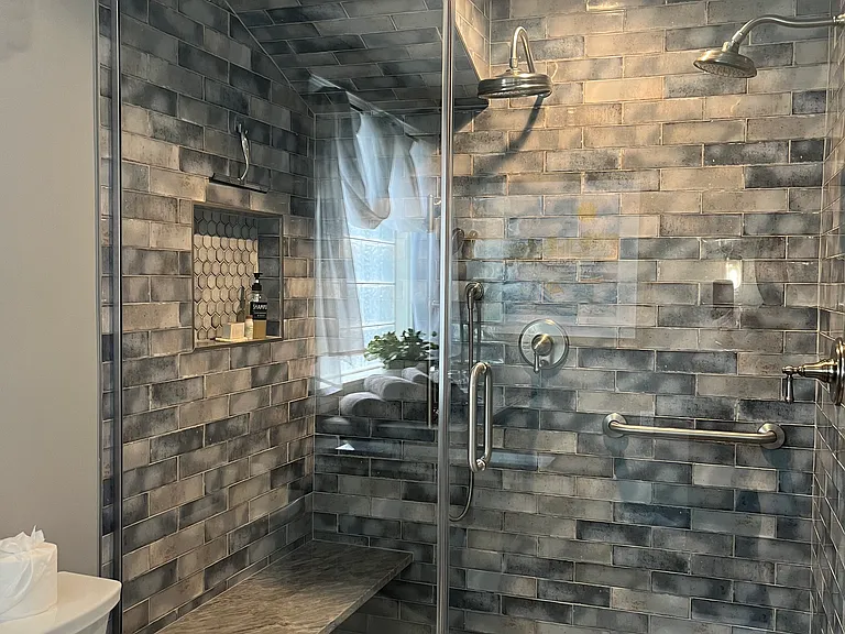 Primary bathroom shower stall with twin Rainmaker shower heads.