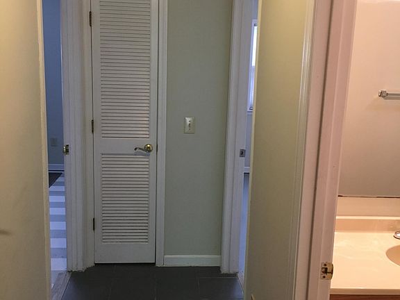 hallway. bathroom with tub on right. two bedrooms at the end of hallway.