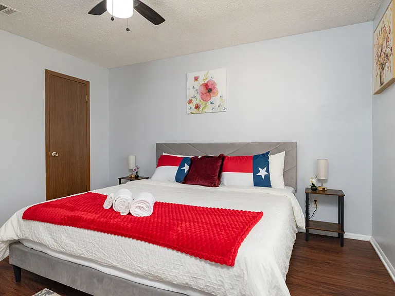 Relax in Bedroom 4, featuring a king bed with patriotic Texas flag pillows and a red throw.