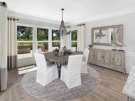 Large Dining Room with numerous windows, decorative lighting and hardwood floors.- Model Representat
