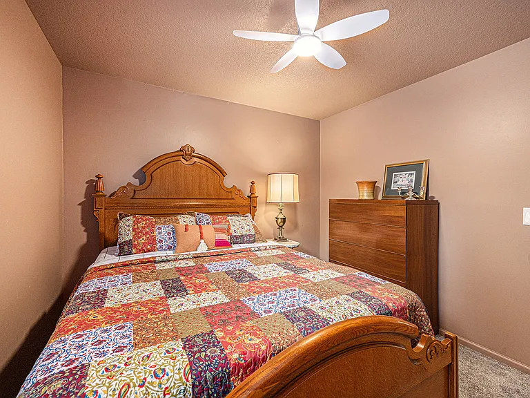 Relax in a cozy bedroom thoughtfully arranged for two, featuring essential furnishings like a side table, lamp, and cabinet for everyday comfort.