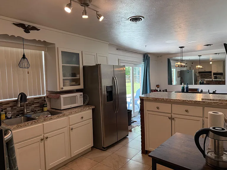 Open kitchen with ample cabinetry, generous counter space, and a stainless-steel fridge, plus easy access to the patio.