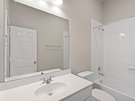 The secondary bath features tile flooring, white cabinetry and light countertops and a shower tub co