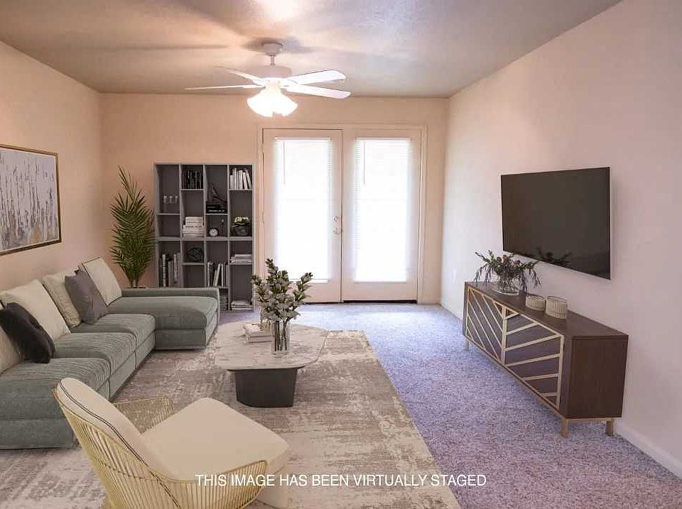 Spacious living area with a ceiling fan and plush carpeting