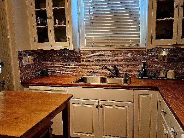 Kitchen has butcher block counters, tile backsplash and large 1 basin sink.