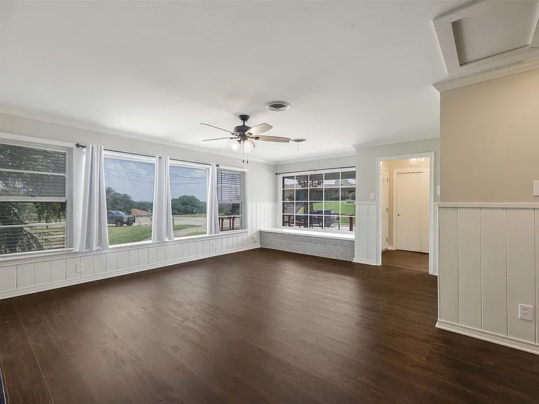 Family room with crown molding, a wealth of natural light, dark wood-type flooring, and ceiling fan