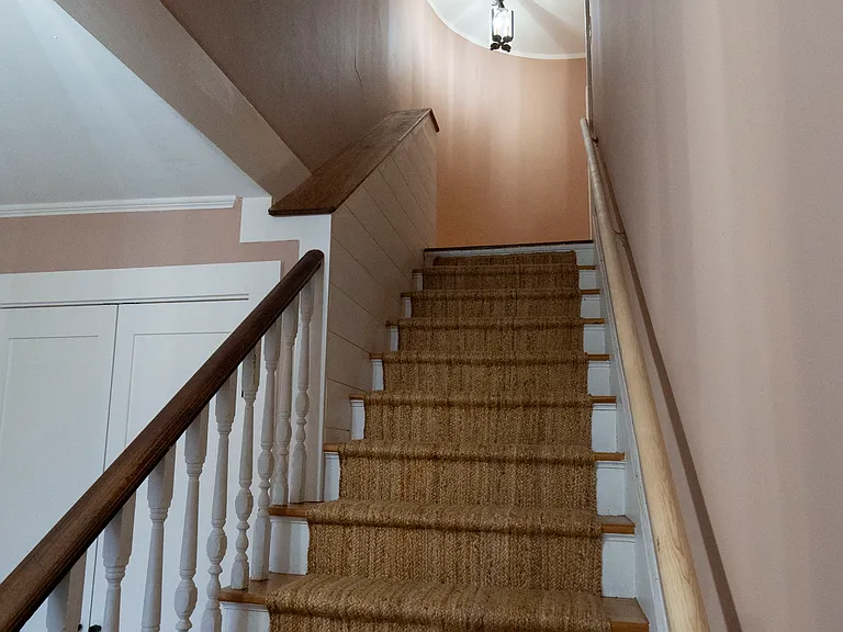 Elegant curved wall at the top of the stair leading to the bedrooms and bathroom. New sisal runner on the stairs for comfort.