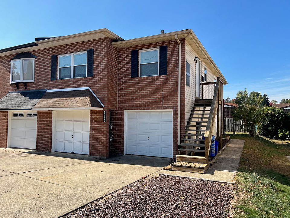 Front of house - top floor and garage on right. Steps up to unit with parking of two cars in front.