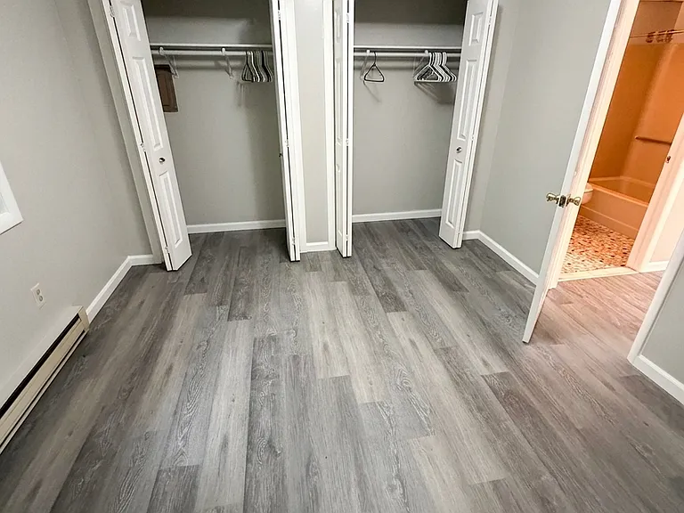 Bedroom featuring two convenient side-by-side closets with bifold doors, situated right next to the bathroom, all updated with freshly painted walls and gorgeous new LVP flooring.
