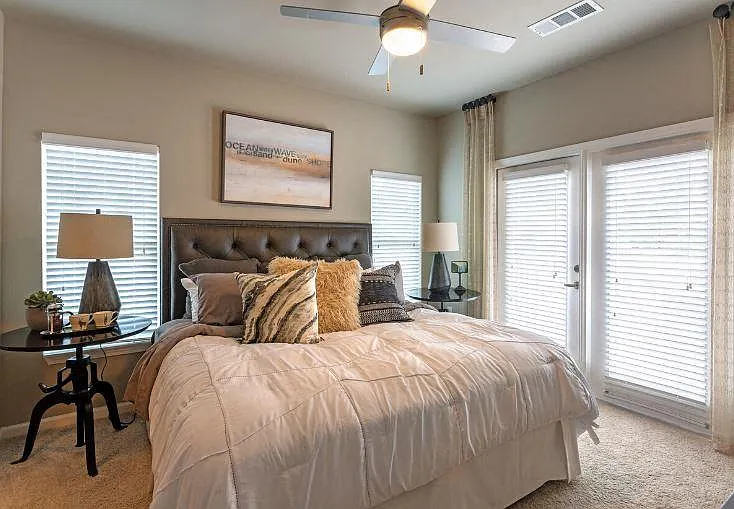 Bedroom with large windows, ceiling fan and carpet flooring