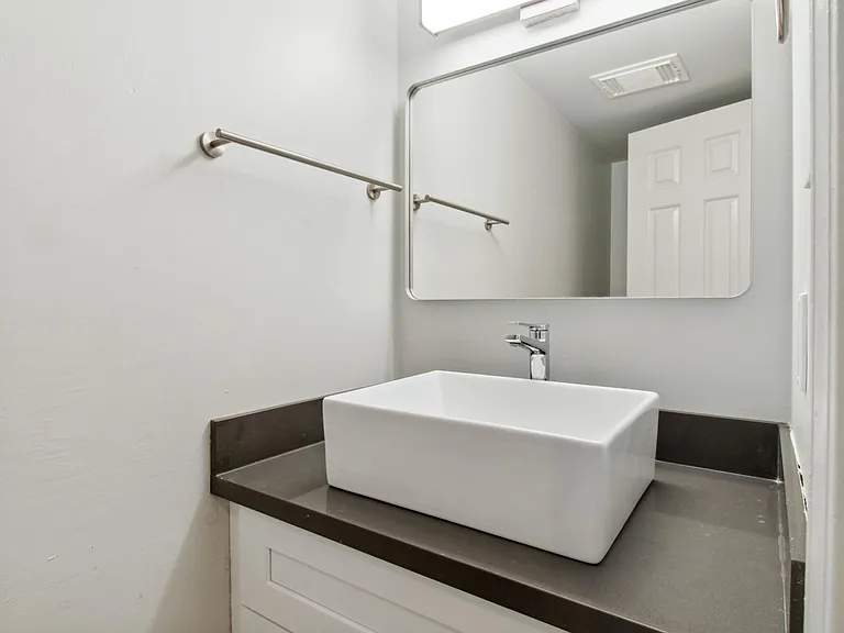 Downstairs half bathroom with brand new vanity, quartz countertop, designer vessel sink, new faucet fixture and towel racks, designer mirror and light fixture.