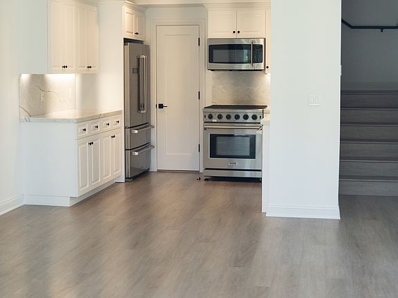 Modern kitchen with stainless steel appliances, quartz countertops, and elegant white cabinetry