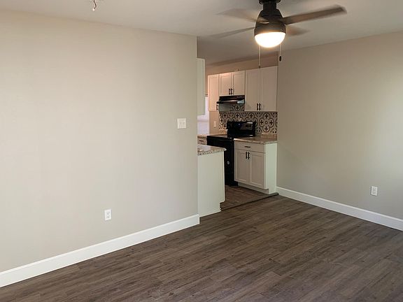 From front door looking into living room towards kitchen. New ceiling fan. New vinyl plank floors. Nice grey walls.