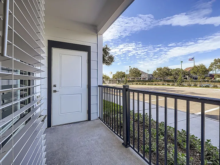 Charming apartment patio with sleek railing offering refreshing city views and blue skies.