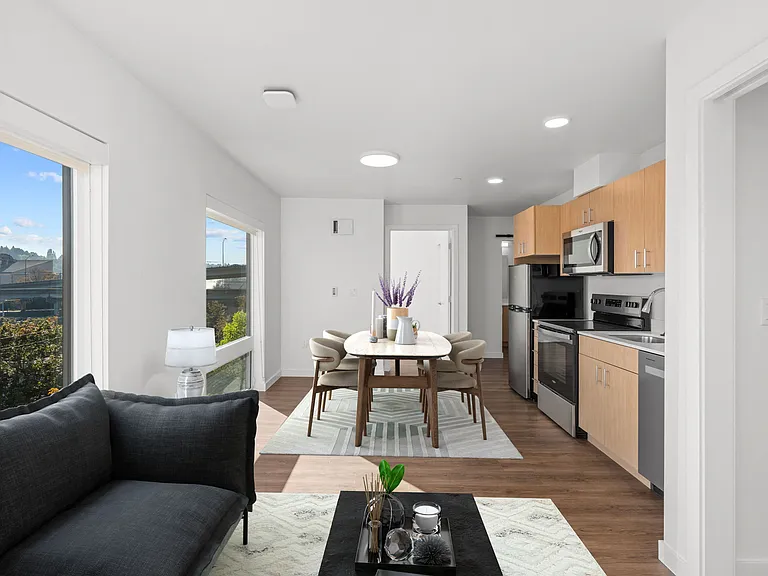 This living room features a couch, table, and kitchen, offering an open layout and inviting atmosphere for comfortable living.