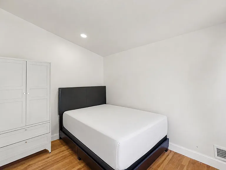 Furnished bedroom with hardwood floors, a full bed, and a wardrobe with drawers for convenient in-room storage.