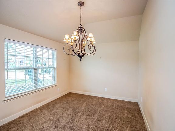 Dining room sits at the front of the home with lovely chandelier, tall ceilings, 2" blinds and a view to the front lawn.