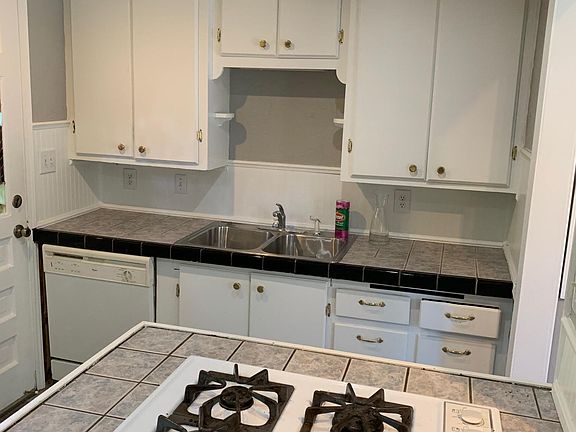 Gas stove, tile counter top, dishwasher, garbage disposal, new refrigerator, and extra storage.