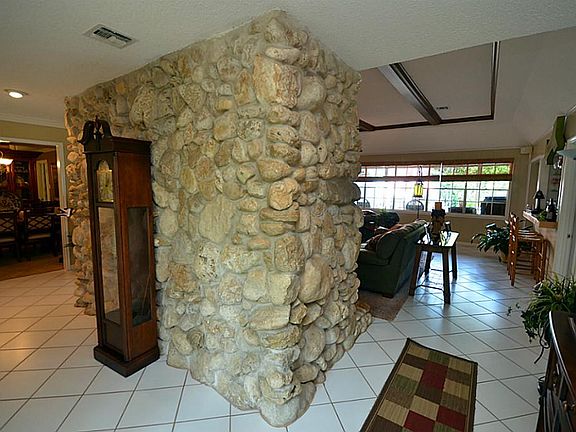 Wonderful foyer entry with floor to ceiling stone enhancing both sides of the fireplace leading you into the family room.