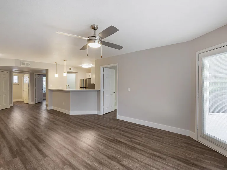 Step into our inviting living room adorned with sleek hardwood floors and complemented by a gentle ceiling fan breeze