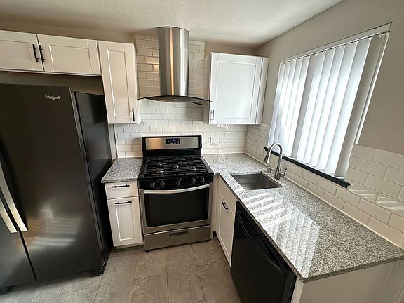 Modern kitchen with sleek granite countertops, stainless steel appliances, and elegant white cabinetry.