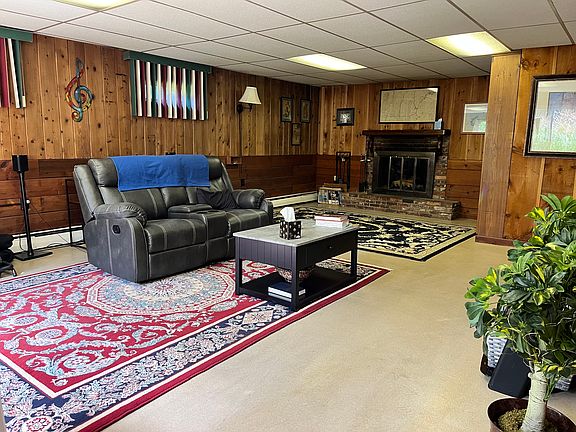 Partially furnished living room. Working fireplace, with built in bookshelf and cabinets on right side wall of fireplace nook.